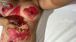 נערה מתבגרת מציירת על גופה האסייתי החשוף עם שפתון בסרטון תוצרת בית